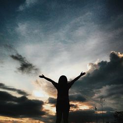 Low angle view of silhouette people standing against cloudy sky