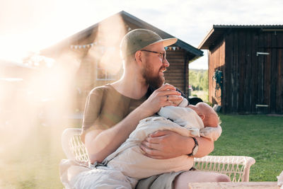 Mid adult man holding baby boy while sitting outside