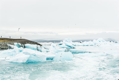 Scenic view of icebergs in sea against sky