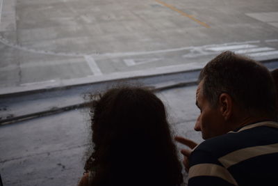 High angle rear view of father showing airport runway to daughter