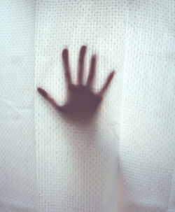 Close-up of hand touching glass window