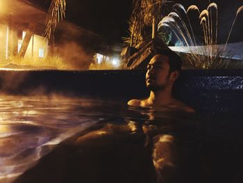 Portrait of shirtless man relaxing in swimming pool