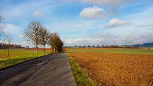 Road amidst field against sky