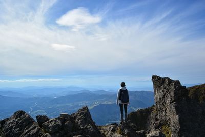 Rear view of woman standing on mountain against sky