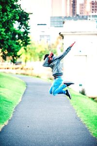 Full length rear view of man jumping in city
