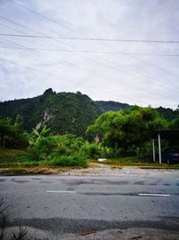 Road by trees against sky