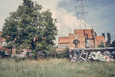 Old building by trees on field against sky