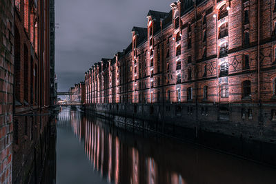 Canal amidst buildings against sky in city