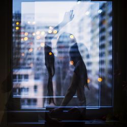 Double exposure of woman standing by window