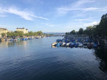 Boats in river by buildings against sky