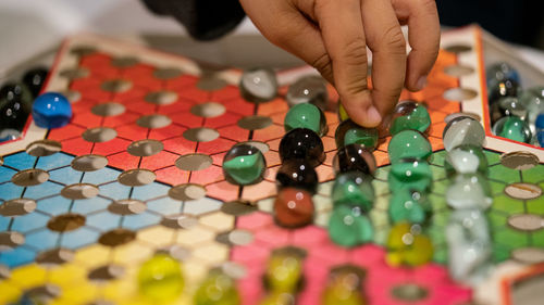 Cropped image of child playing with marbles on colorful container