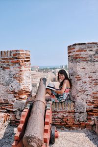 Woman sitting on fort against clear sky