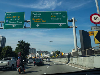 Road sign on street in city against sky