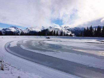 Scenic view of frozen lake and mountains against sky