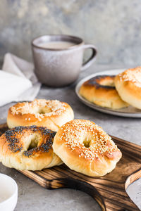 Bagels with poppy seeds and sesame seeds on a plate and a cup of coffee on the table