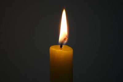 Close-up of burning candle against black background