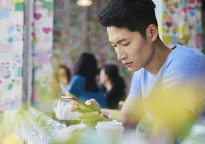 Young man using smart phone while sitting in cafe
