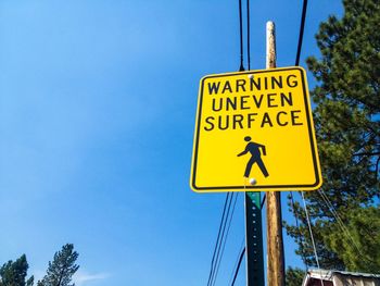 Low angle view of sign board against blue sky