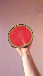 Close-up of hand holding watermelon against pink background