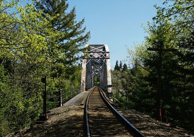 Railroad tracks over bridge by trees against sky