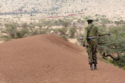 Rear view of man walking on dirt road