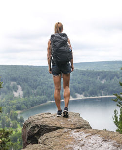 Rear view of woman standing on rock looking at sea