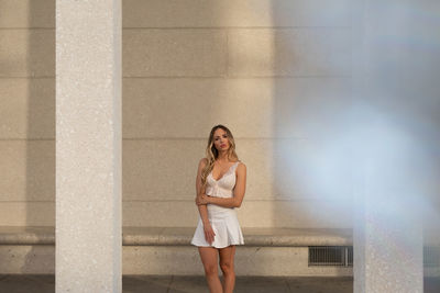 Full length portrait of woman standing against wall