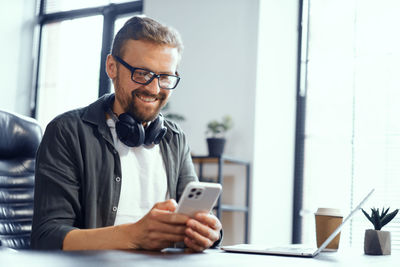 Young man using mobile phone while sitting at office