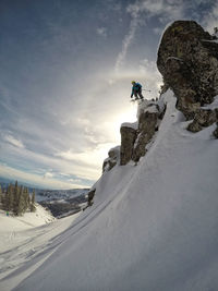 Low angle view of boy skiing on snow covered mountain against sky