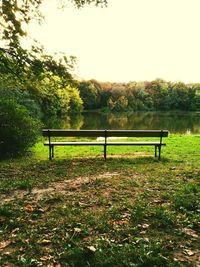 Park bench on field against clear sky