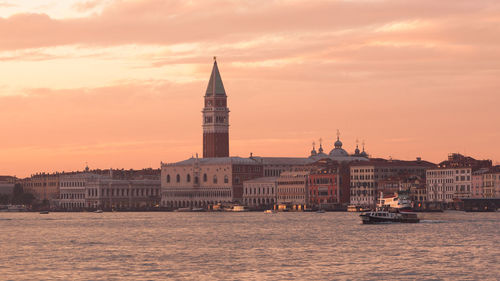 View of buildings at waterfront against cloudy sky