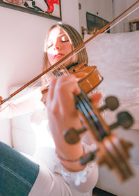 Young woman playing violin while sitting at home