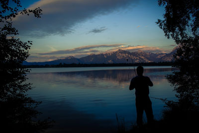 Rear view of silhouette man on lake against sky