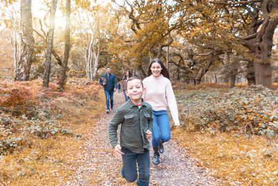 Full length portrait of a smiling young woman with autumn trees