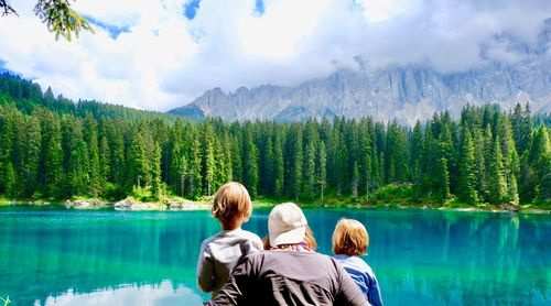 Rear view of people looking at lake against mountain