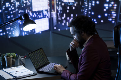 Side view of woman using laptop at office