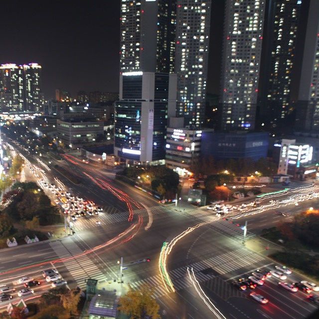 illuminated, night, city, architecture, building exterior, built structure, transportation, high angle view, light trail, road, long exposure, cityscape, city life, street, traffic, city street, motion, speed, car, skyscraper