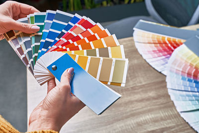 Midsection of person holding multi colored umbrella on table