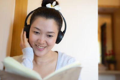 Portrait of smiling young woman using mobile phone at home