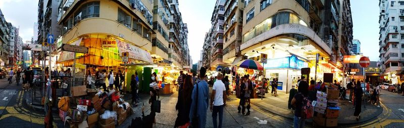 Panoramic view of crowd walking in city against sky