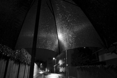 Close-up of wet glass below illuminated light at night