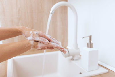 Cropped hand washing hands in sink