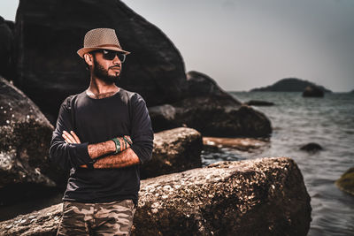 Young man standing on rock by sea