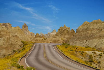 Road amidst rock formations against blue sky