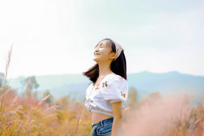 Young woman standing against sky
