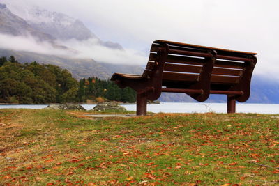 Empty bench on field against sky