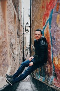 Portrait of young woman sitting on wall