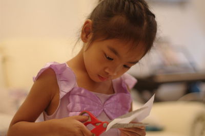 Cute girl cutting paper at home