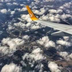 Cropped image of airplane wing over clouds