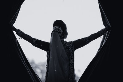 Low angle view of woman standing against sky